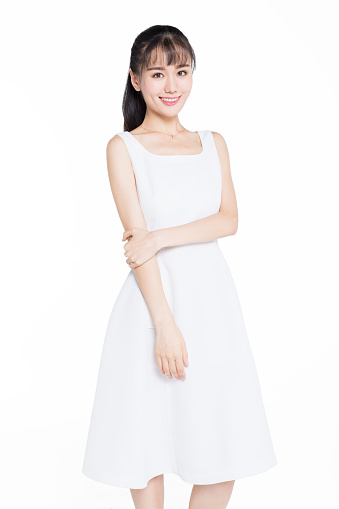 studio shot of beautiful asian woman wearing white dress posing over white background.