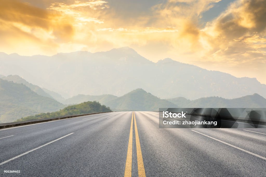 asphalt road and mountains with foggy landscape at sunset asphalt road and mountains with foggy nature landscape at sunset Road Stock Photo