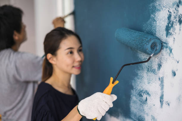 istock Young asian couple painting interior wall 905375422