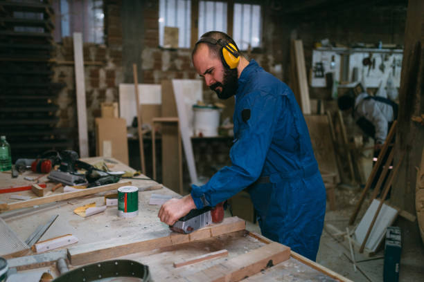 istock Young man working with wood and wearing protective workwear in the workshop 905375446