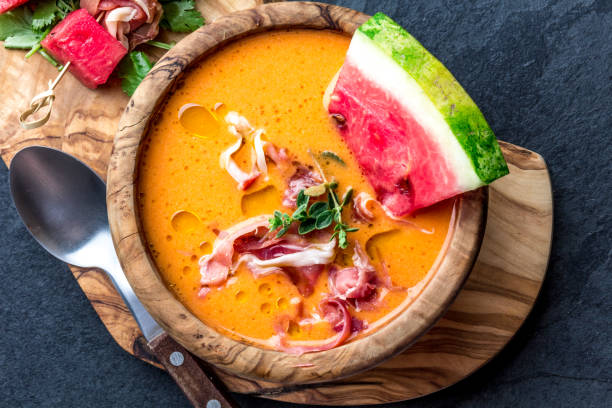 Salmorejo soup with watermelon. Traditional spanish cold tomato soup with watermelon and ham serrano in olive wooden bowl, slate background, top view Salmorejo soup with watermelon. Traditional spanish cold tomato soup with watermelon and ham serrano in olive wooden bowl, slate background, top view. spanish fork utah stock pictures, royalty-free photos & images