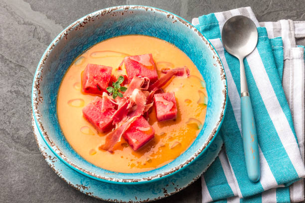 Salmorejo soup with watermelon. Traditional spanish cold tomato soup with watermelon and ham serrano in blue plate, slate background, top view Salmorejo soup with watermelon. Traditional spanish cold tomato soup with watermelon and ham serrano in blue plate, slate background, top view. spanish fork utah stock pictures, royalty-free photos & images