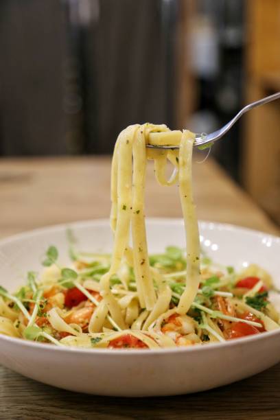 istock using stainless fork pick pasta / linguine with scrimp scampi in a white dish on a wooden table up 905386496
