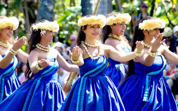 Hawaiian dancers entertaining visitors on a canoe float at the Polynesian Cultural Center, a popular tourist attraction of Oahu. stock photo