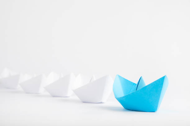 istock Leadership concepts with blue paper ship leading among white 905390088