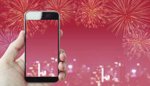 istock Hand holding mobile smart phone, pink background with fireworks and Bokeh light 905401096