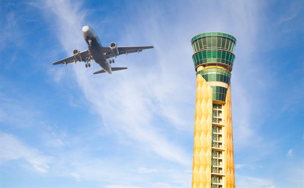 Airplane flying and air traffic control tower. New Delhi, India Airplane flying over air traffic control tower and blue sky. india airport stock pictures, royalty-free photos & images
