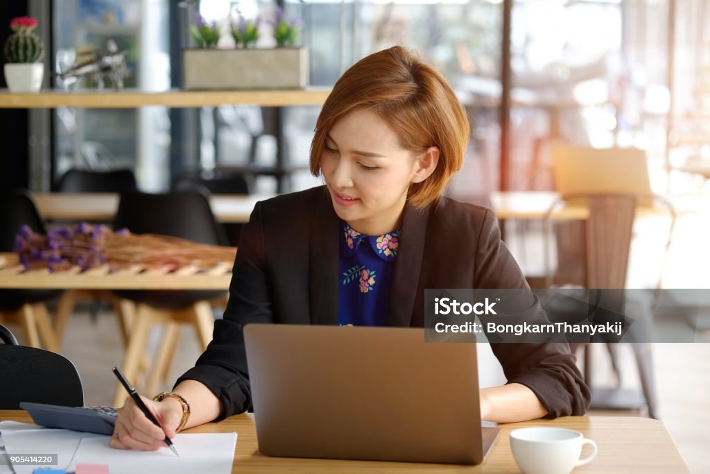 Cropped shot of a young Asian businesswoman making notes in cafe. Internet Stock Photo