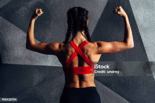 Back View Portrait Of A Fitness Woman Showing Biceps Stock Photo - Download Image Now