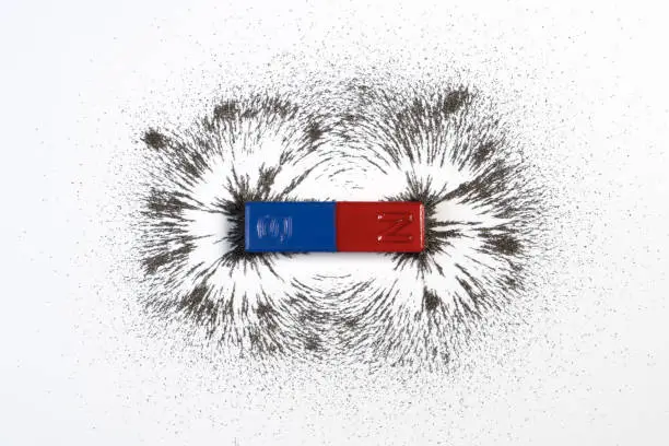 Red and blue bar magnet or physics magnetic with iron powder magnetic field on white background. Scientific experiment in science class in school.