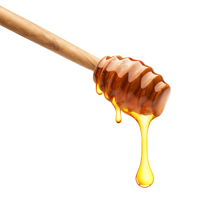 Honey dripping from dipper on isolated white background