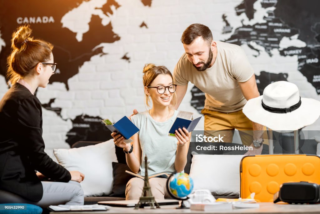 Couple at the travel agency office Young lovely couple sitting with manager at the travel agency office prepairing for a summer vacation Couple - Relationship Stock Photo