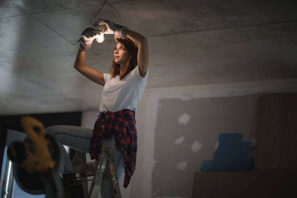 eletricista feminina lâmpada de aperto durante o processo de renovação em casa. - changing lightbulb - fotografias e filmes do acervo