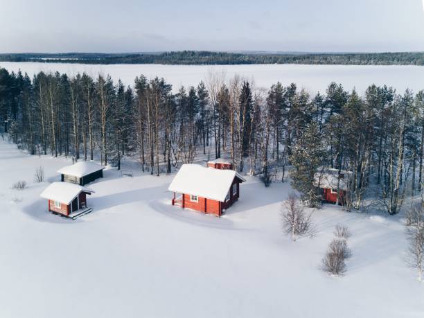scenic winter picture of a cottage near the lake and trees covered in snow. - finland sauna lake house imagens e fotografias de stock