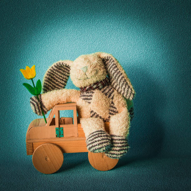 Teddy rabbit on theblue background sitting in a light on the  wooden car toy, quadrant combination