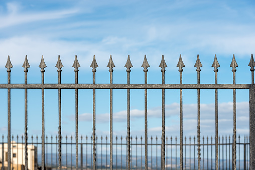 Close-up of a forged iron fence with arrows with blue sky and clouds