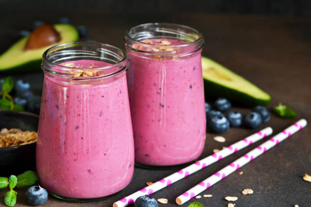 Organiik drink. Smoothies of yogurt with avocado, honey, blueberries and granola on a dark background. Easy snack. stock photo