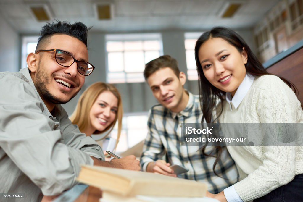 Students Posing in Class Multi-ethnic group of cheerful students looking at camera and smiling sitting at desk in lecture hall of modern college University Student Stock Photo