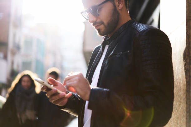 istock Young handsome man tourist using smartphone application to find right direction in urban setting, trendy hipster guy searching street number on mobile version of city map on his modern cellular 905464632