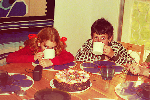Vintage image of a boy and a girl drinking hot chocolate with a table