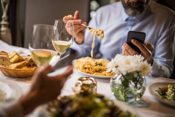 istock Unrecognizable people using mobile phones on a lunch in a restaurant. 905467764