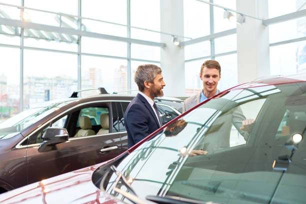 istock Young Man Choosing New Car in Showroom 905467944