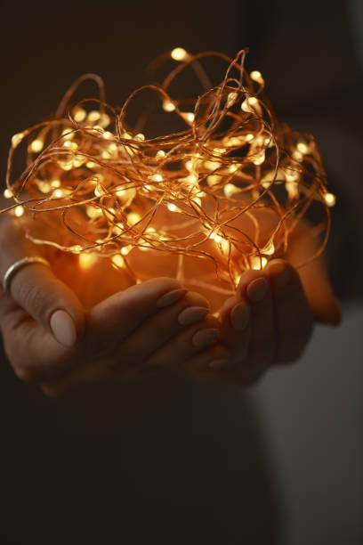 istock Woman hands holding string of lights in the dark. 905468664