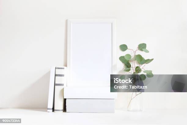 White Blank Wooden Frame Mockup With A Green Eucalyptus Branches In Glass Bottle And Pile Of Books Lying On The Table Poster Product Design Styled Stock Feminine Photography Home Decor Stock Photo - Download Image Now