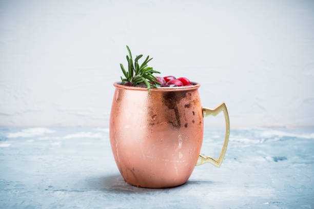 Cold christmas Moscow Mule cocktail in copper mug on the rustic background