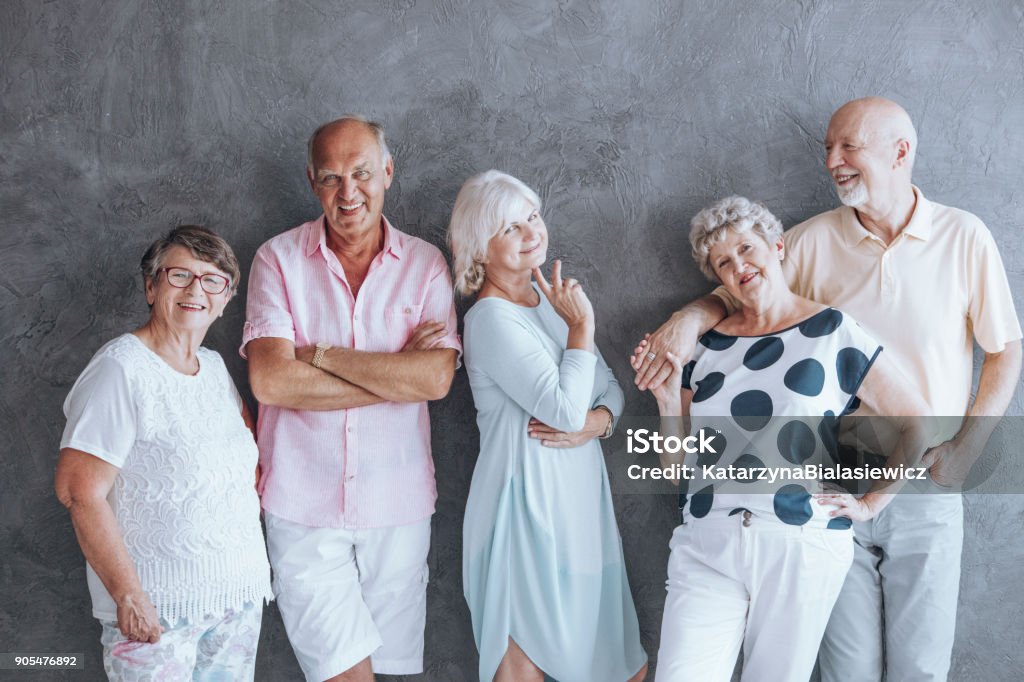 Active seniors fashion statement Group of seniors leaning against a gray wall wearing casual clothes. Active seniors fashion statement. Nursing Home Stock Photo