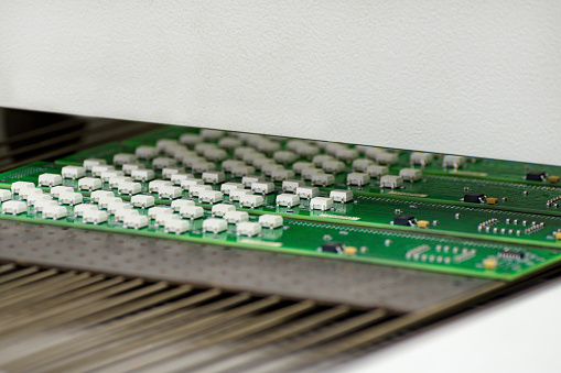 Electronic printed circuit board at the output of air convection reflow oven.  Manufacture of electronic components.