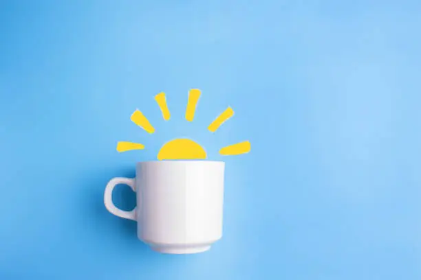 sun and white cup on blue background. good morning concept