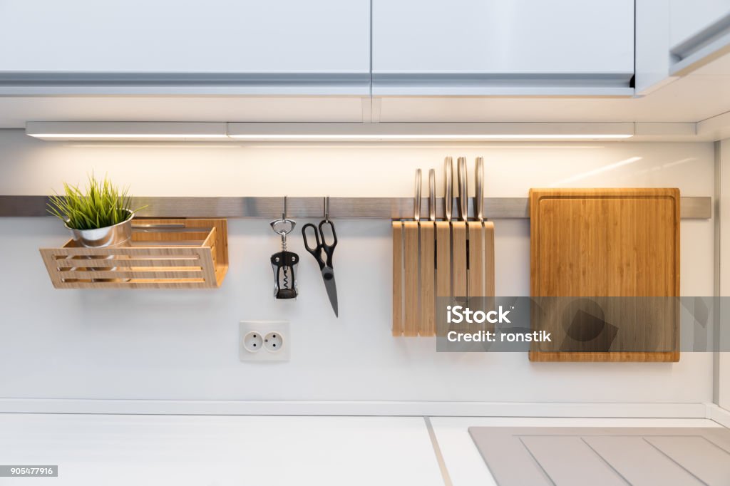 kitchenware hanging on the rail in the white glossy kitchen Kitchen Stock Photo
