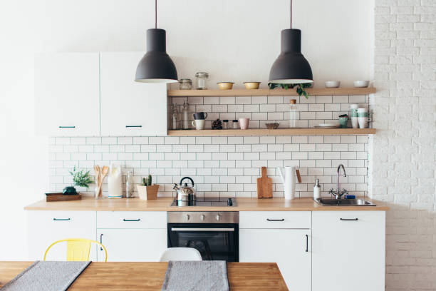 moderno novo interior luz de cozinha com mobiliário branco e mesa de jantar. - cozinha doméstica - fotografias e filmes do acervo