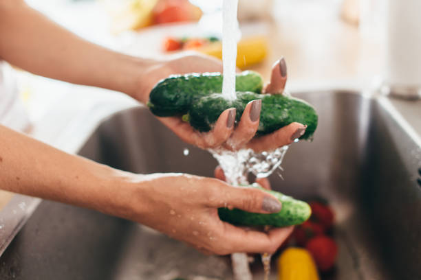 istock Woman washing cucumbers in kitchen sink close up. 905481348
