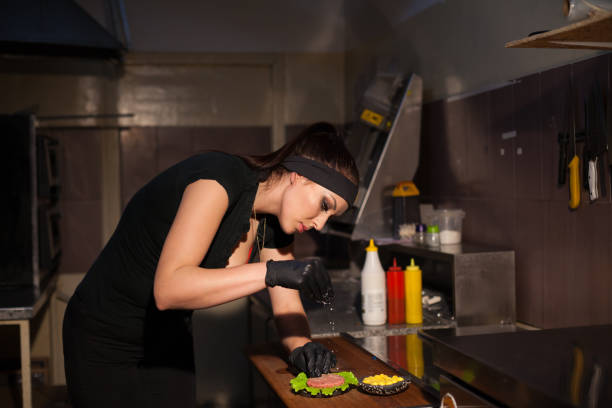 istock beautiful girl Cook prepares the kitchen Burger 905484296