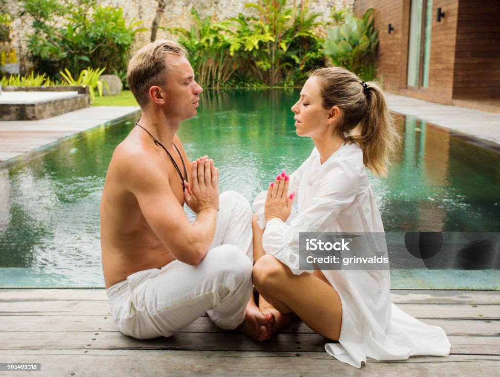 Couple meditate together Caucasian ethnicity couple meditate together by the pool Couple - Relationship Stock Photo