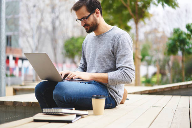 istock Handsome male copywriter working on project in irregular hours schedule with  tight deadlines creating advertising content for clients using laptop computer connected to wireless network in college 905504450