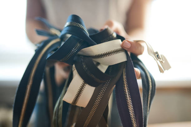istock Female tailor holding zippers in hands 905509678