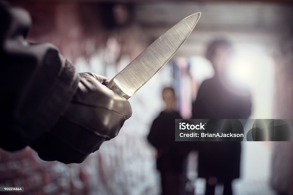 Criminal with knife weapon threatening woman in underpass crime Criminal with knife weapon threatening woman and child in underpass crime Knife Crime Stock Photo