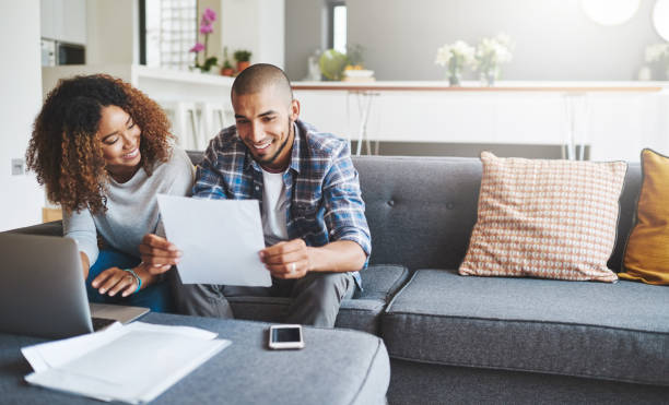 Building a tight household budget Shot of a young couple going through their paperwork together at home household insurance stock pictures, royalty-free photos & images