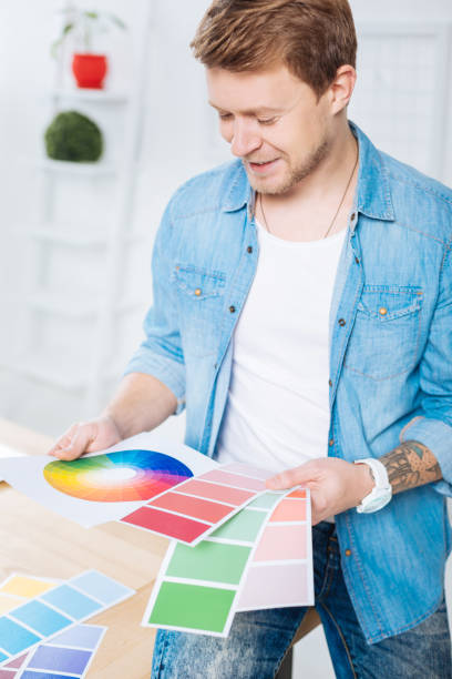 istock Smiling designer sitting in his office and looking at different color palettes 905531204