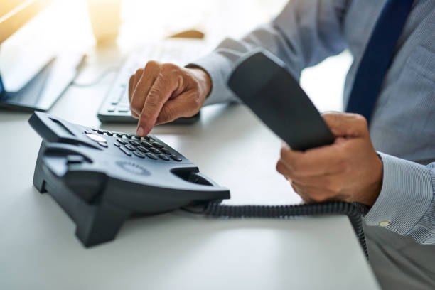 He's ready to assist Cropped shot of an unrecognizable businessman dialing a number on a telephone at work answering photos stock pictures, royalty-free photos & images
