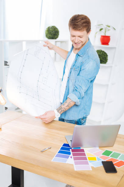 istock Positive engineer holding a scheme and looking at the laptop 905535788