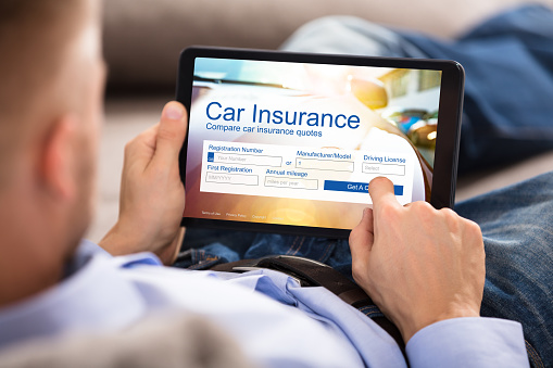 Close-up Of A Man Filling Car Insurance Form On Digital Tablet