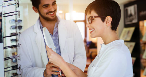 istock Beautiful woman with optician trying eyeglasses 905540194