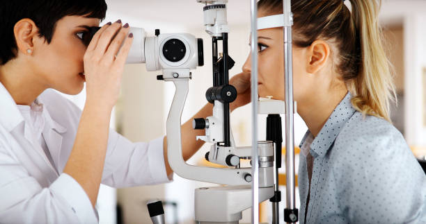 Attentive optometrist examining female patient on slit lamp Attentive optometrist examining female patient on slit lamp in ophthalmology clinic eye test equipment stock pictures, royalty-free photos & images