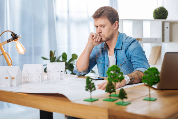 istock Thoughtful engineer sitting at the table and looking concentrated 905540858