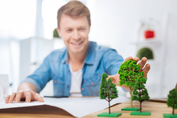 istock Positive engineer touching miniature trees and smiling happily 905541242