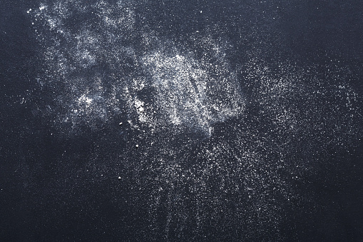Dusty chalk textured abstract background. White powder splash covering black board surface, top view, copy space